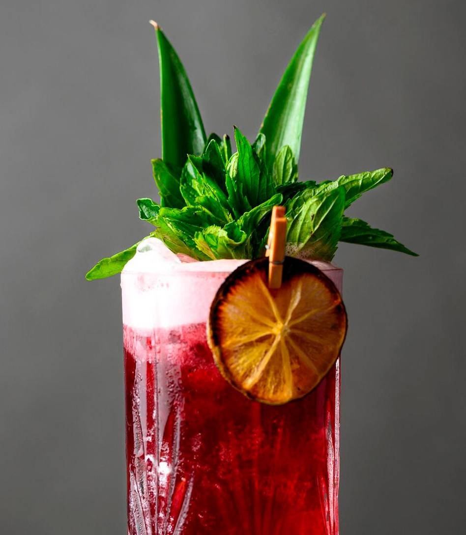 Handcrafted mocktails with floral decoration on a sleek white mobile bar at an indoor event.